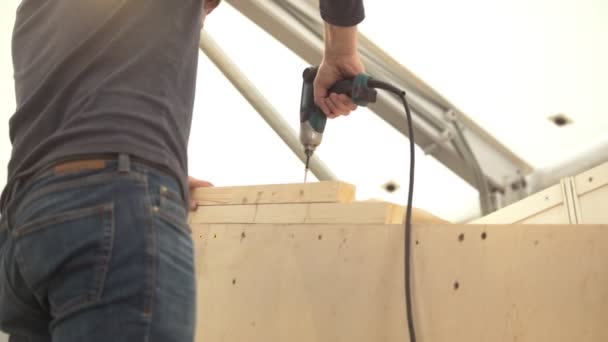 Craftsman with electric screwdriver drill the wood — Stock Video