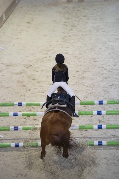 Jovem criança menina cavaleiro pulando no cavalo sobre obstáculo em show jumping concorrência — Fotografia de Stock