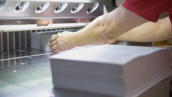 Le mani di lavoratore tolgono risme di carta da taglio maschine — Foto Stock