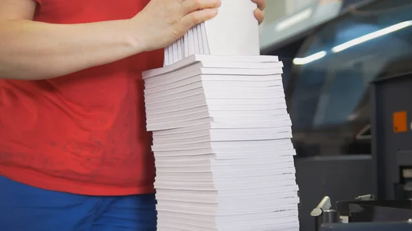 As mãos do funcionário feminino dobram uma pilha de papel na tipografia — Fotografia de Stock