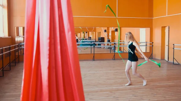 Sutra merah di depan wanita muda melatih latihan senam dengan pita-de-fokus — Stok Foto