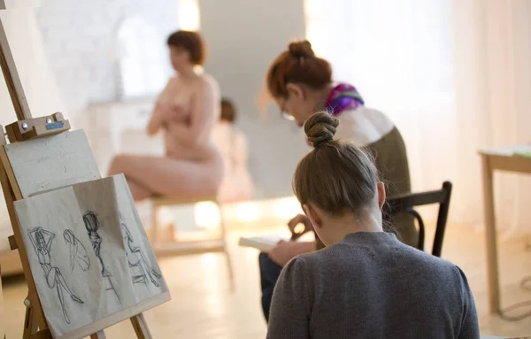 Jóvenes artistas femeninas dibujando una modelo desnuda en clase de dibujo —  Fotos de Stock