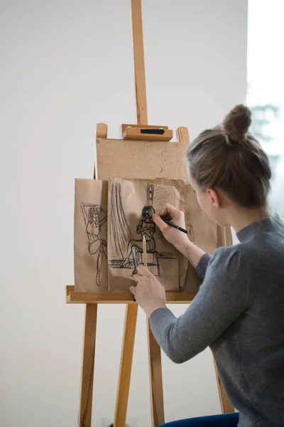 Rear view of female painter draws on the easel human figure — Stock Photo, Image