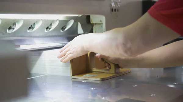 Trabalhadora dobra uma pilha de papel na tipografia — Fotografia de Stock