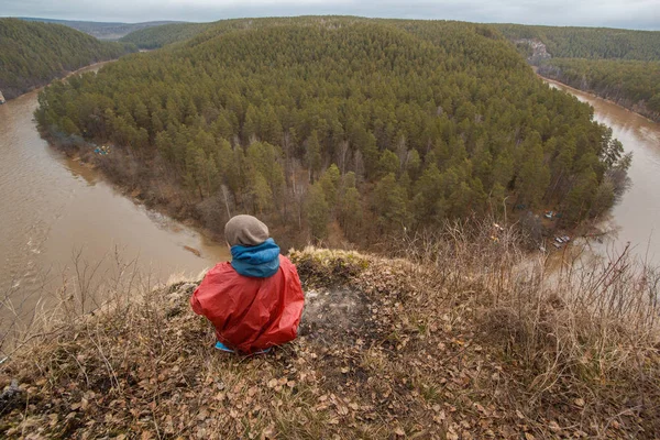 Randonneur assis au sommet de la colline regardant la rivière — Photo