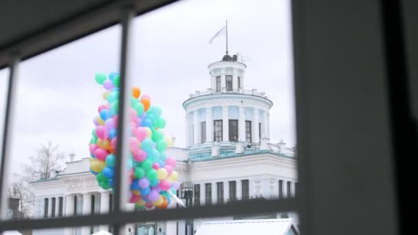 Manojo de globos de colores fuera de la ventana en el fondo de la construcción — Vídeo de stock