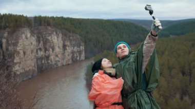 Genç çift tepe dağ nehir arka plan üzerinde selfie yapar