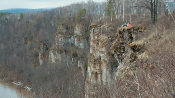 Хіллтоп з видом на гірську річку, що оточує ліс, молодих туристів, що сидять на відстані — стокове відео