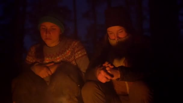 Chicas jóvenes cansadas bostezan sentadas en la hoguera en el bosque por la noche — Vídeos de Stock