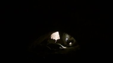 Karanlık mağaranın içine dört ayak üzerinde kask karıştıran genç Explorer'da