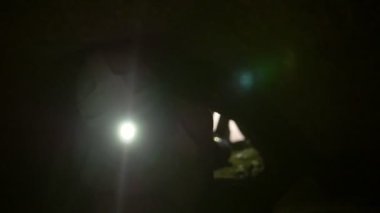 Kask ile el feneri karıştıran karanlık mağaranın içinde dört ayak üzerinde genç kaşifler