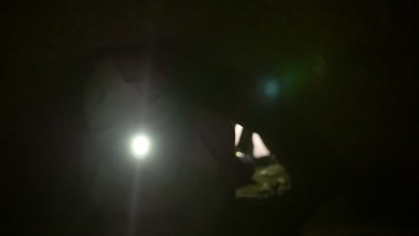 De jeunes explorateurs dans des casques avec des lampes de poche se bousculent à quatre pattes dans la grotte sombre 