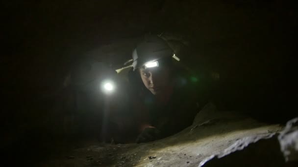 Two young hikers explorers stuck in the narrow hole in dark cave — Stock Video
