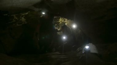 Grup genç speleologists karanlık dar mağaranın araştırıyor