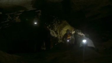 Grup genç speleologists tırmanma kadar karanlık dar mağarada