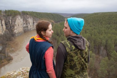 Bir uçurumun kenarında duran yürüyüşçü genç çift ve holdind dağ Nehri üzerinde eller