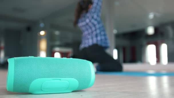 Drahtloser Lautsprecher vor junger Frau, die sich auf dem Teppich ausstreckt — Stockvideo