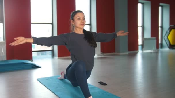 Jovem mulher esbelta realiza exercícios de alongamento no tapete na sala de fitness — Vídeo de Stock