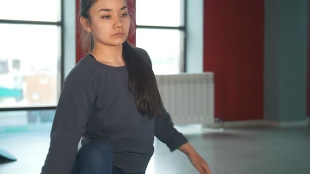 Молодая женщина выполняет упражнения на растяжку на ковре в классе фитнеса — стоковое видео