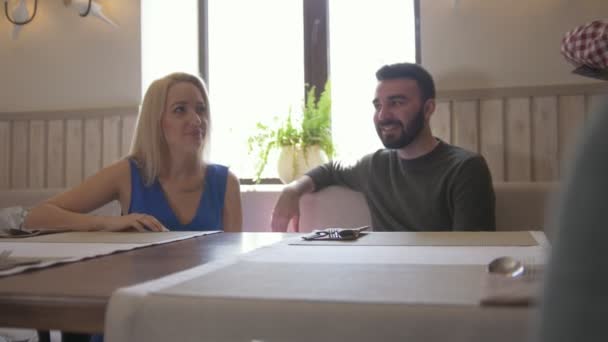 Молодая пара берет меню, чтобы сделать заказ в кафе — стоковое видео