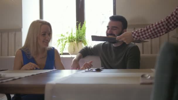 Gelukkige Kaukasische paar neemt het menu in het café — Stockvideo