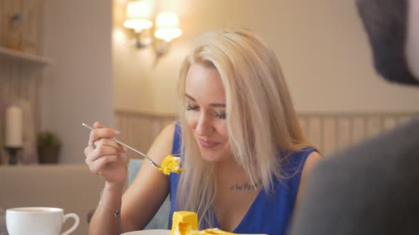 Young beautiful woman tries the piece of sweet cake in the cafe — Stock Video