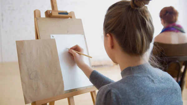 Дві жінки-художники ескізують модель в яскравому класі малювання — стокове фото