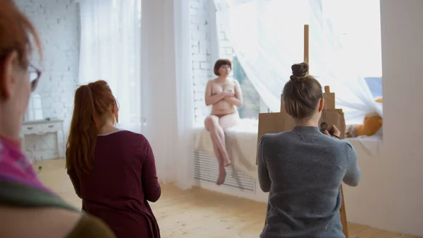 スタジオの描画で裸モデルと芸術的なエチュードを実行する若い女性アーティスト — ストック写真