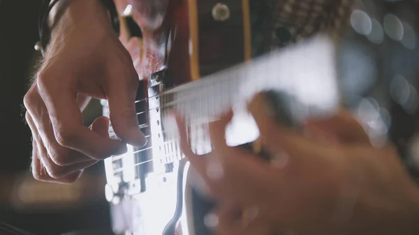 Músico masculino toca la guitarra, las manos cierran, se centran en el diapasón de la guitarra — Foto de Stock