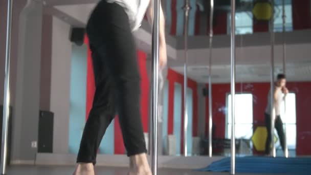 Jeune homme athlétique effectuant des exercices de pole dance dans un studio — Video