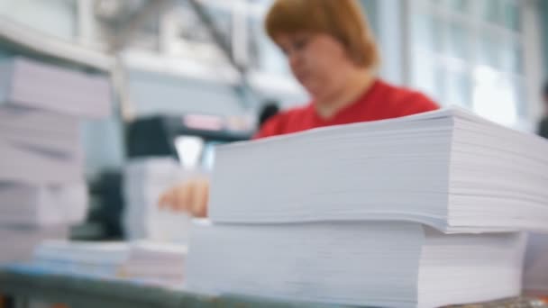 Pilha de papel na frente de trabalhadora ordenando um papel na tipografia — Vídeo de Stock