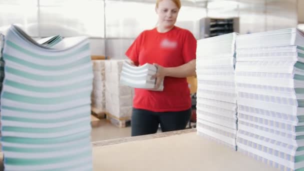 Female worker puts the printed magazines in stacks on the table in the typography — Stock Video