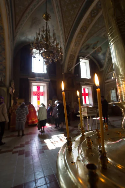 Vela de cera na frente de pessoas na igreja ortodoxa — Fotografia de Stock