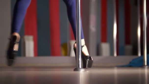 Slim gambe femminili in nero scarpe col tacco alto che ballano su una pole dance — Video Stock