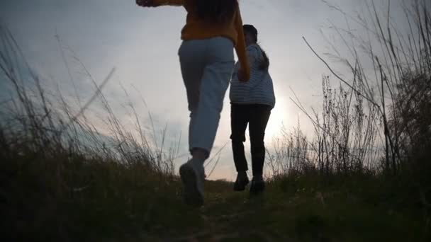 Дві жінки друзі тікають від камери на заході сонця — стокове відео