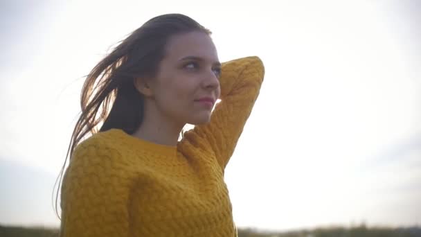 Mooie jonge vrouw permanent buiten in gele jas bij zonsondergang — Stockvideo