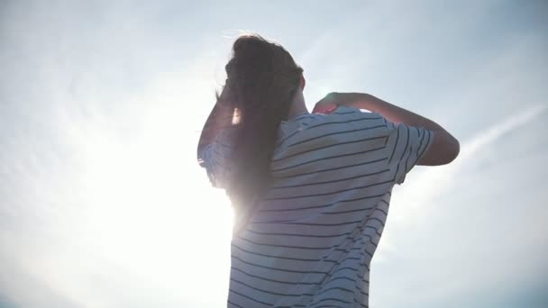 Mujer joven de pelo largo volando en el viento al atardecer — Vídeo de stock