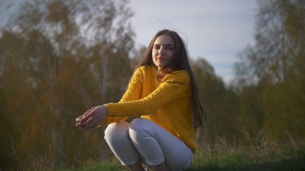 Joven mujer feliz con el pelo largo sentado en la hierba en el bosque — Vídeos de Stock