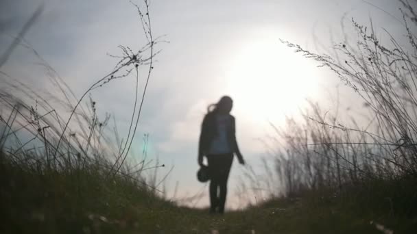 Jovem silhueta feminina caminhando no campo ao pôr do sol — Vídeo de Stock