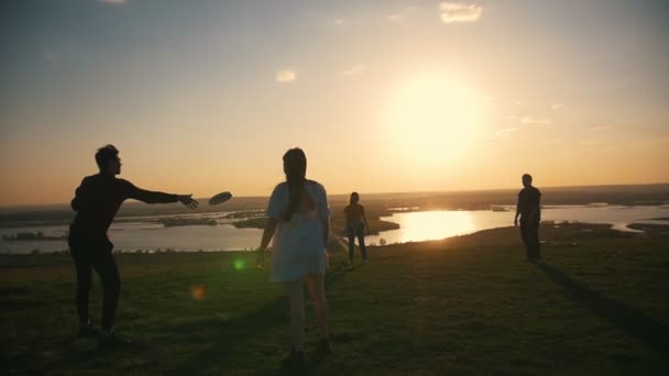 Młodzi przyjaciele gry frisbee na wzgórzu o zachodzie słońca — Wideo stockowe