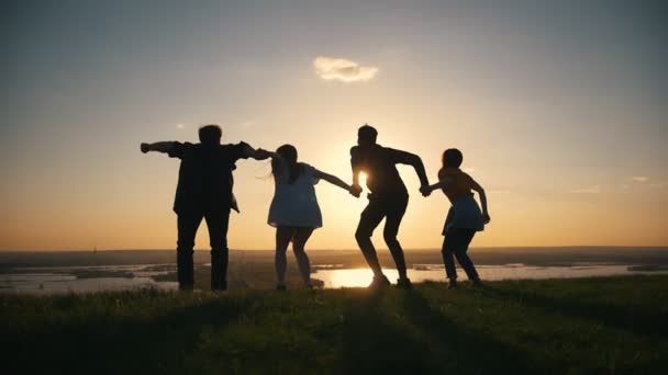 Группа счастливых подростков, поднимающих руки, прыгающих на закате — стоковое видео