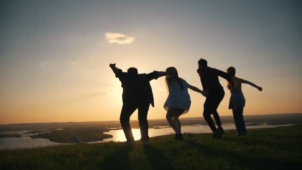 Happy young friends raising hands jumping at sunset on the hill — Stock Video