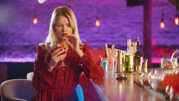 Gorgeous young woman sitting by the bartender stand - drinking a beverage from the straw — Stock Video