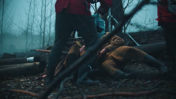 Nos bastidores das filmagens soldados feridos deitados no chão na floresta enevoada e conversando cameraman de pé na frente deles — Vídeo de Stock