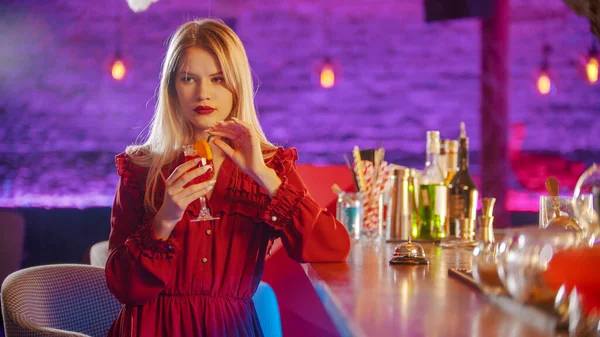 Прекрасная молодая женщина, сидящая у стойки бармена - пьет напиток из соломы и смотрит в сторону — стоковое фото