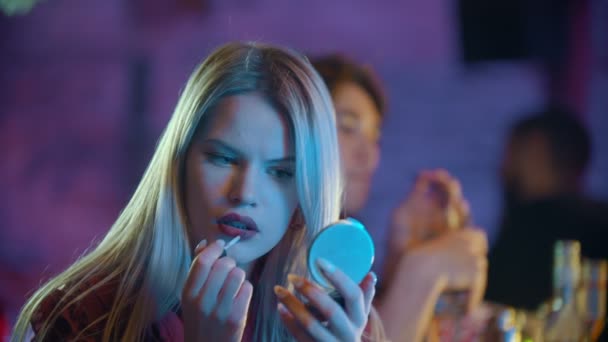 Underbar ung blond kvinna sitter vid bartendern stå och applicera rött läppstift på hennes läppar och titta i spegeln — Stockvideo
