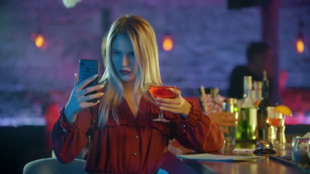 Mujer joven sentada junto al camarero y usando su teléfono - tomando una selfie con una bebida — Vídeos de Stock