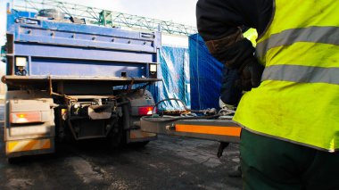 Kargo nakliyatı. Koruyucu refleks yelekli bir işçi olay yerinde duruyor.