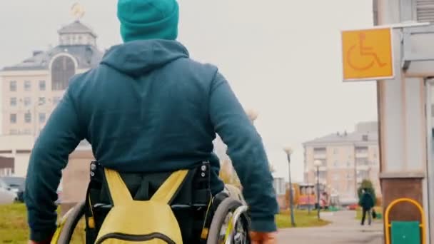 Behinderter im Rollstuhl sieht das Schild "Behindert" und bewegt sich auf den Platz zu — Stockvideo