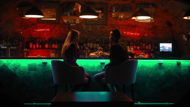 Un couple envoûtant ayant un rendez-vous au bar assis debout et riant — Video